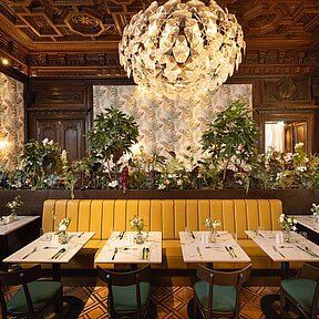 Bel étage with set tables, lush greenery and chandeliers
