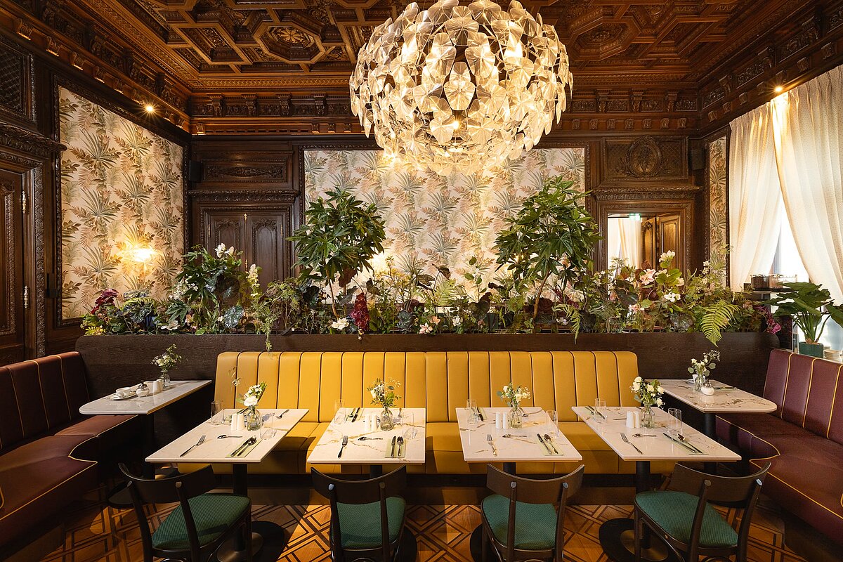 Bel étage with set tables, lush greenery and chandeliers