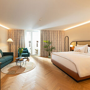 Bright and spacious hotel room with sofa bed and chair