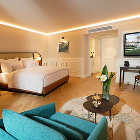 Spacious hotel room featuring a sofa, chair, working desk, and smart TV