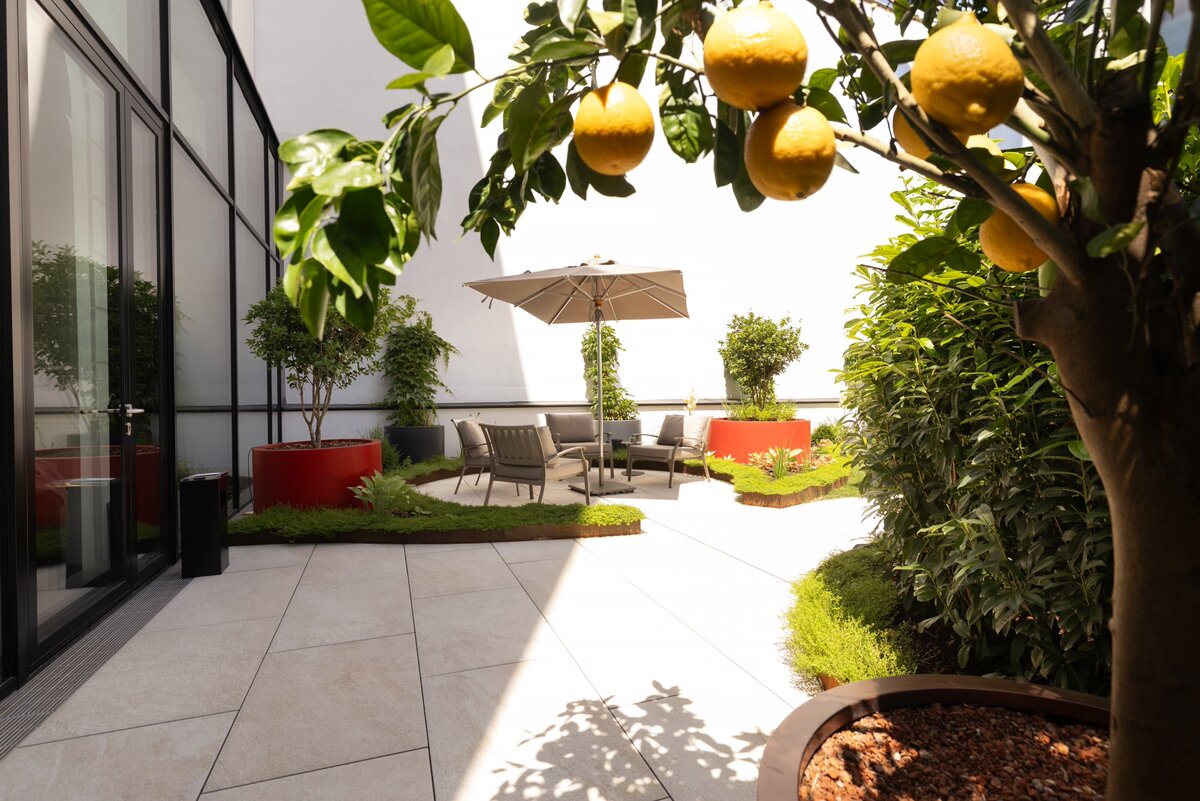 Gartendetail mit Orangenbaum und gemütlicher Sitzecke