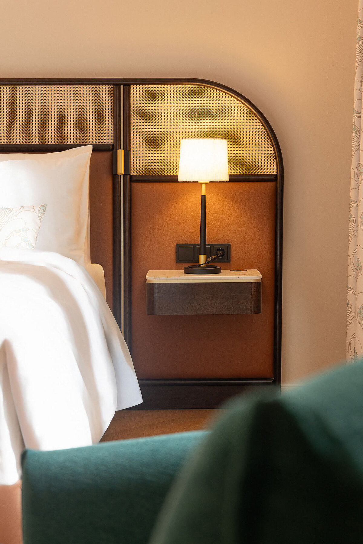 Detail view of hotel bed with bedside table and ambient lighting