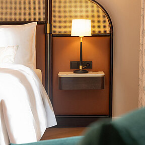 Detail view of  hotel bed with bedside table and ambient lighting