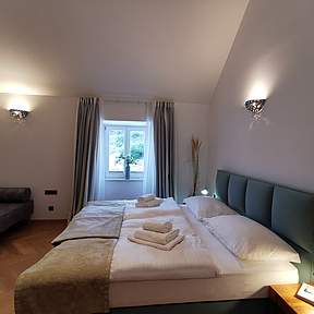 Schlafzimmer mit Doppelbett und kleinem Sofa 