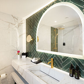 Hotel bathroom vanity with backlit mirror