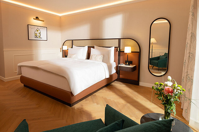 Bright hotel room featuring a king-size bed, mirror, and chair
