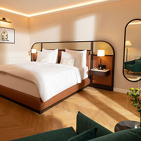 Bright hotel room featuring a king-size bed, mirror, and chair