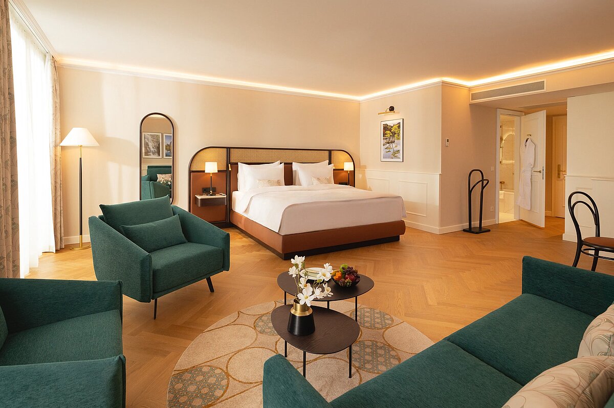 Junior Suite with double bed, green sofa and two lounge chairs