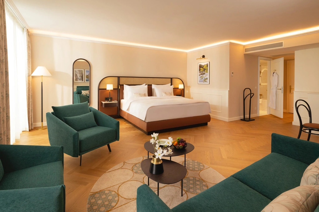 Junior Suite with double bed, green sofa and two lounge chairs
