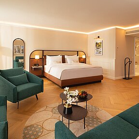 Junior Suite with double bed, green sofa and two lounge chairs